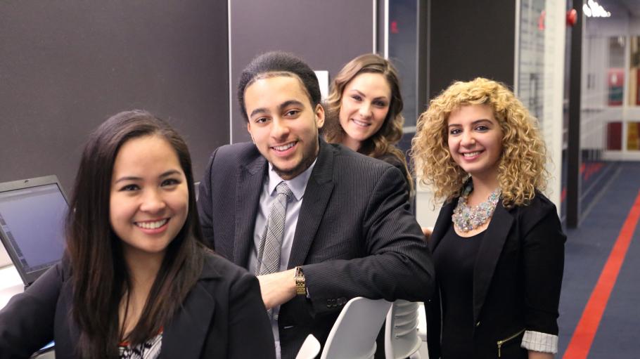 Business students sitting and posing together for a picture in business attire. 
