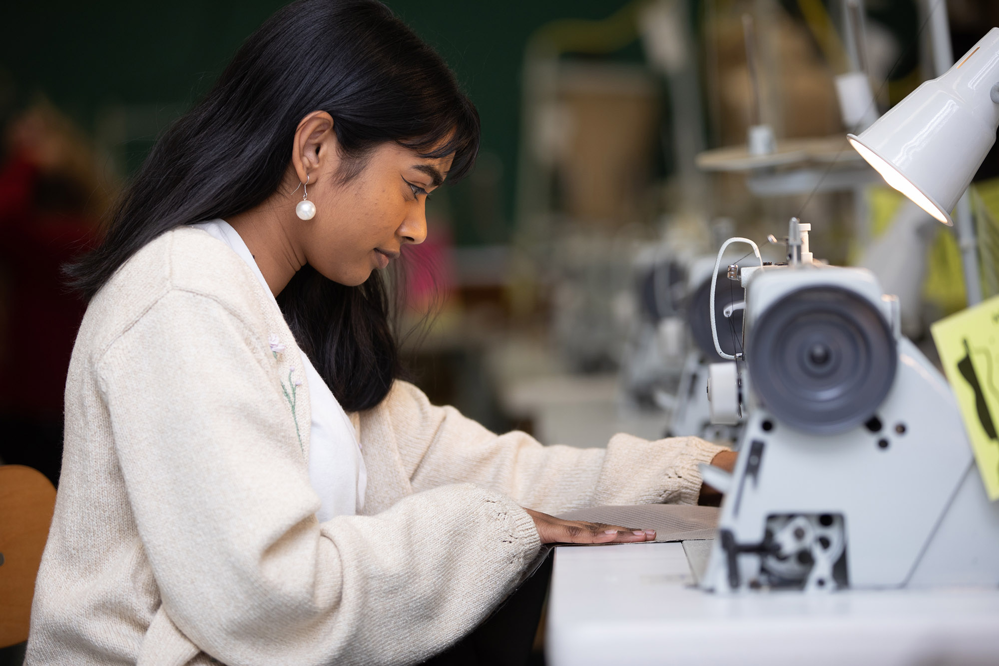 A fashion student sitting at a sewing machine