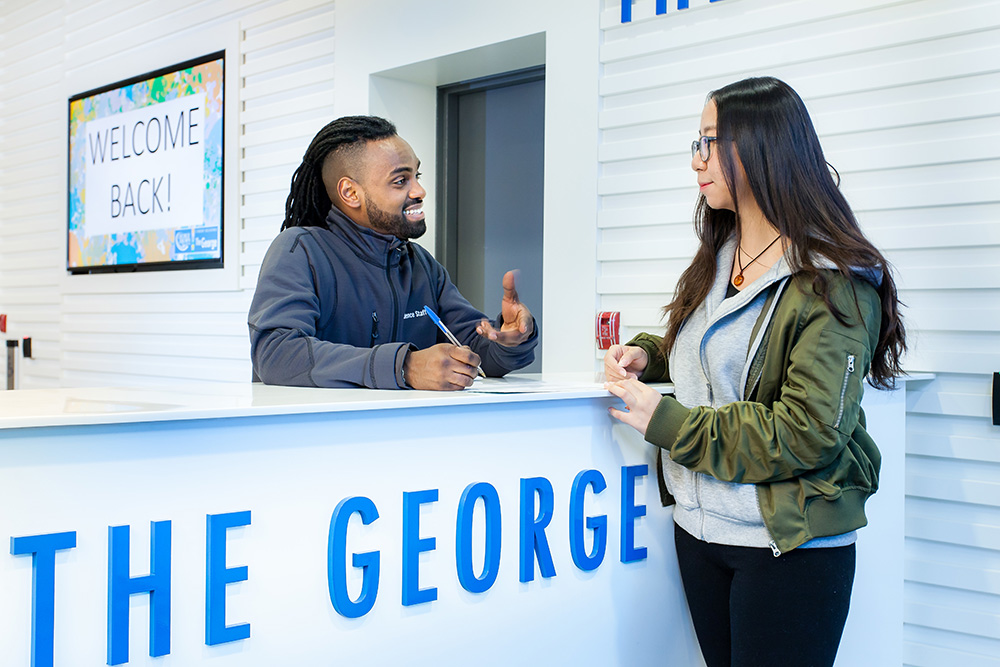 A front desk worker welcoming a resident at The George student residence