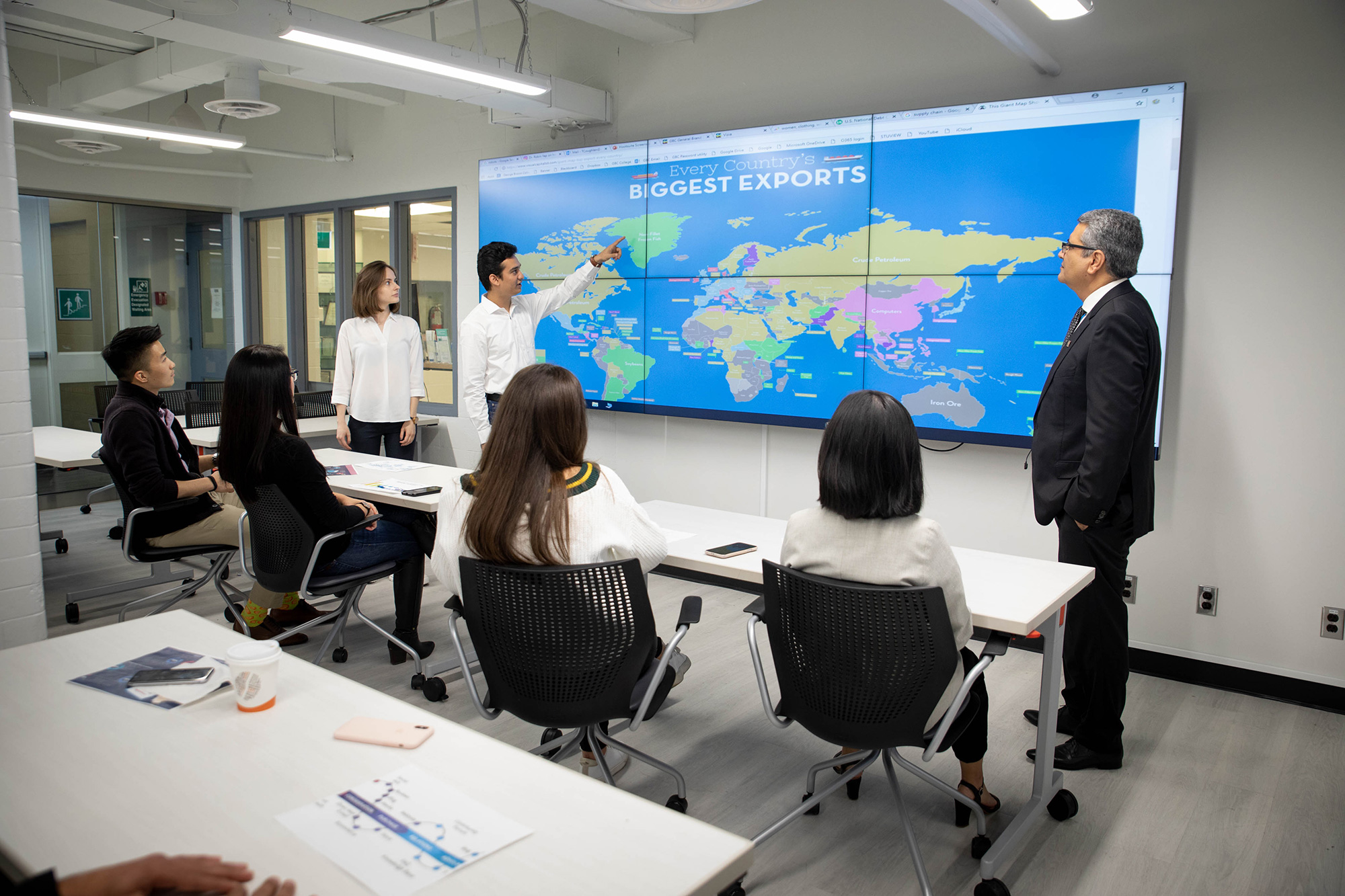 Students pointing to a digital map in a business classroom