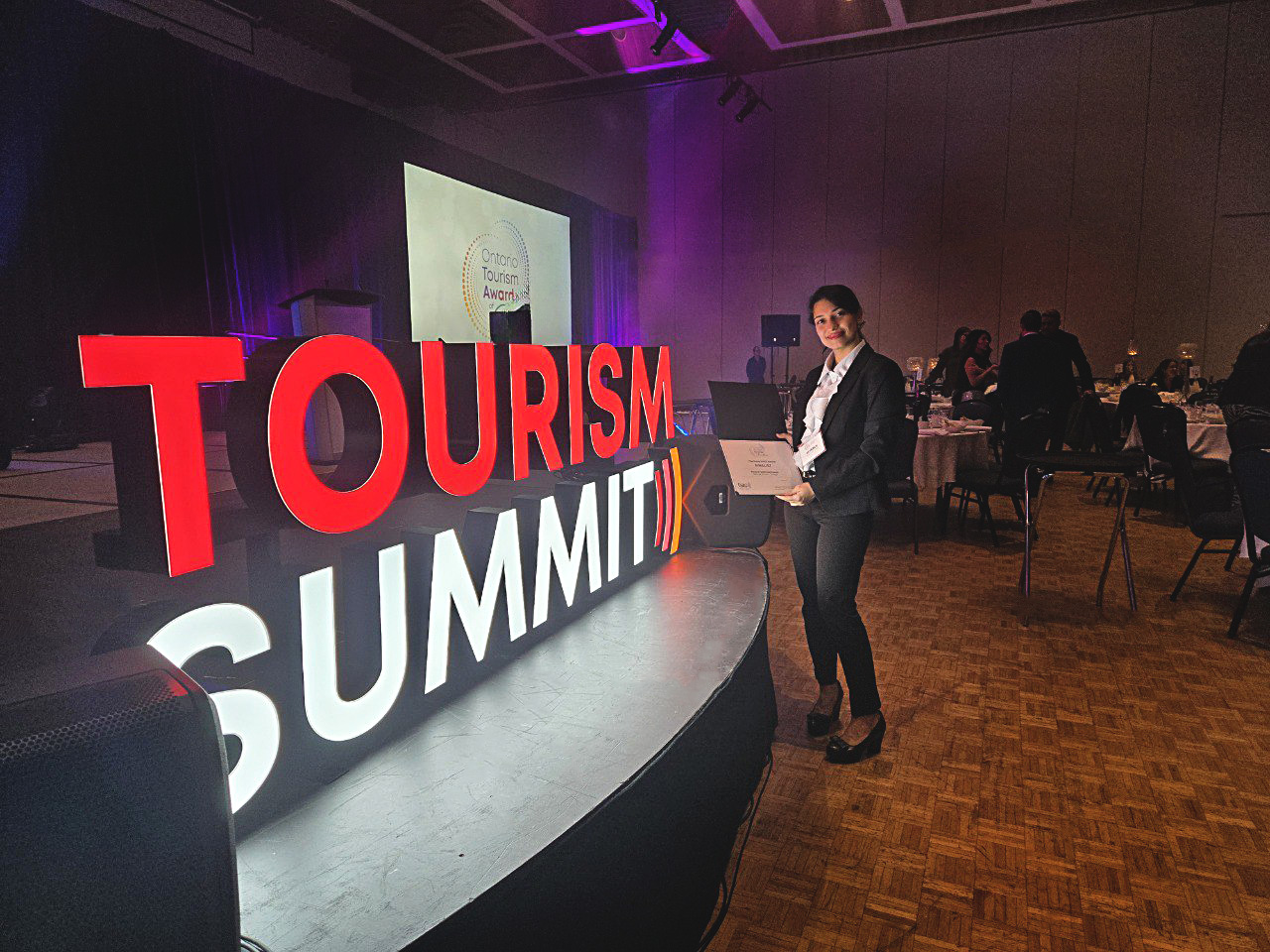 Setareh Soleimaninasab stands in front of the Toronto Summit sign at the Ontario Tourism Industry Association awards event