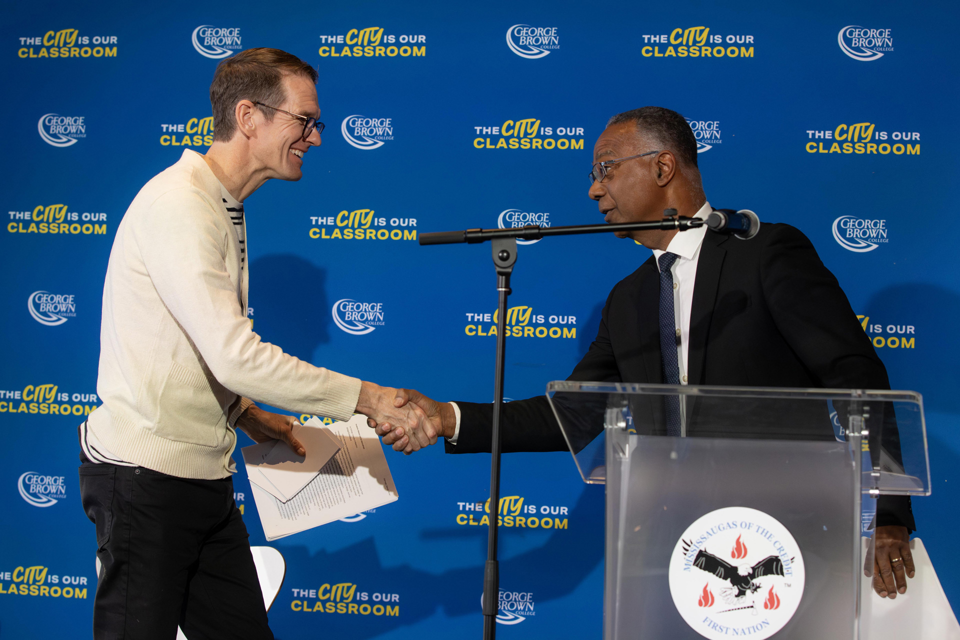 Two men shake hands on stage