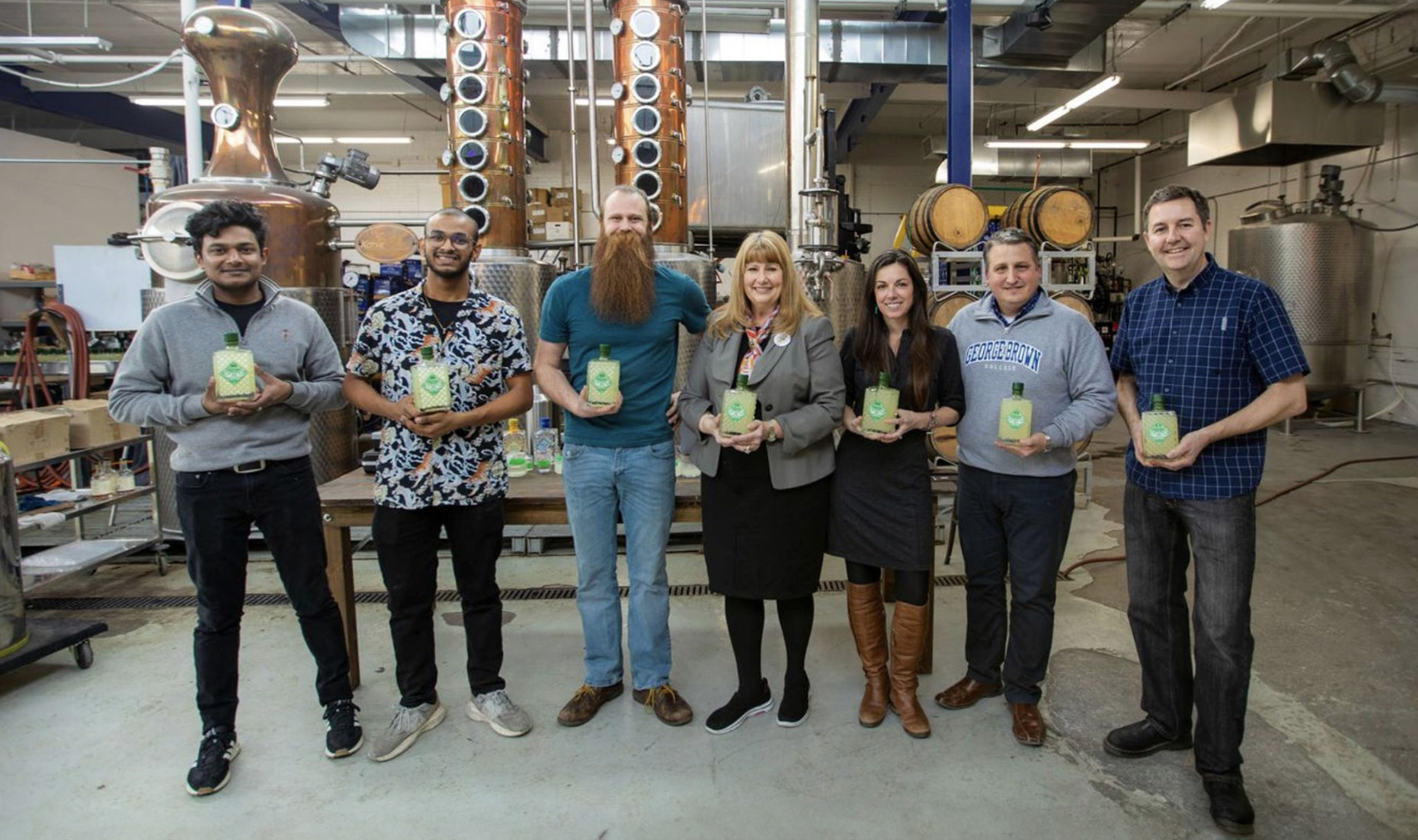 A group of people hold Citronino bottles in a distillery