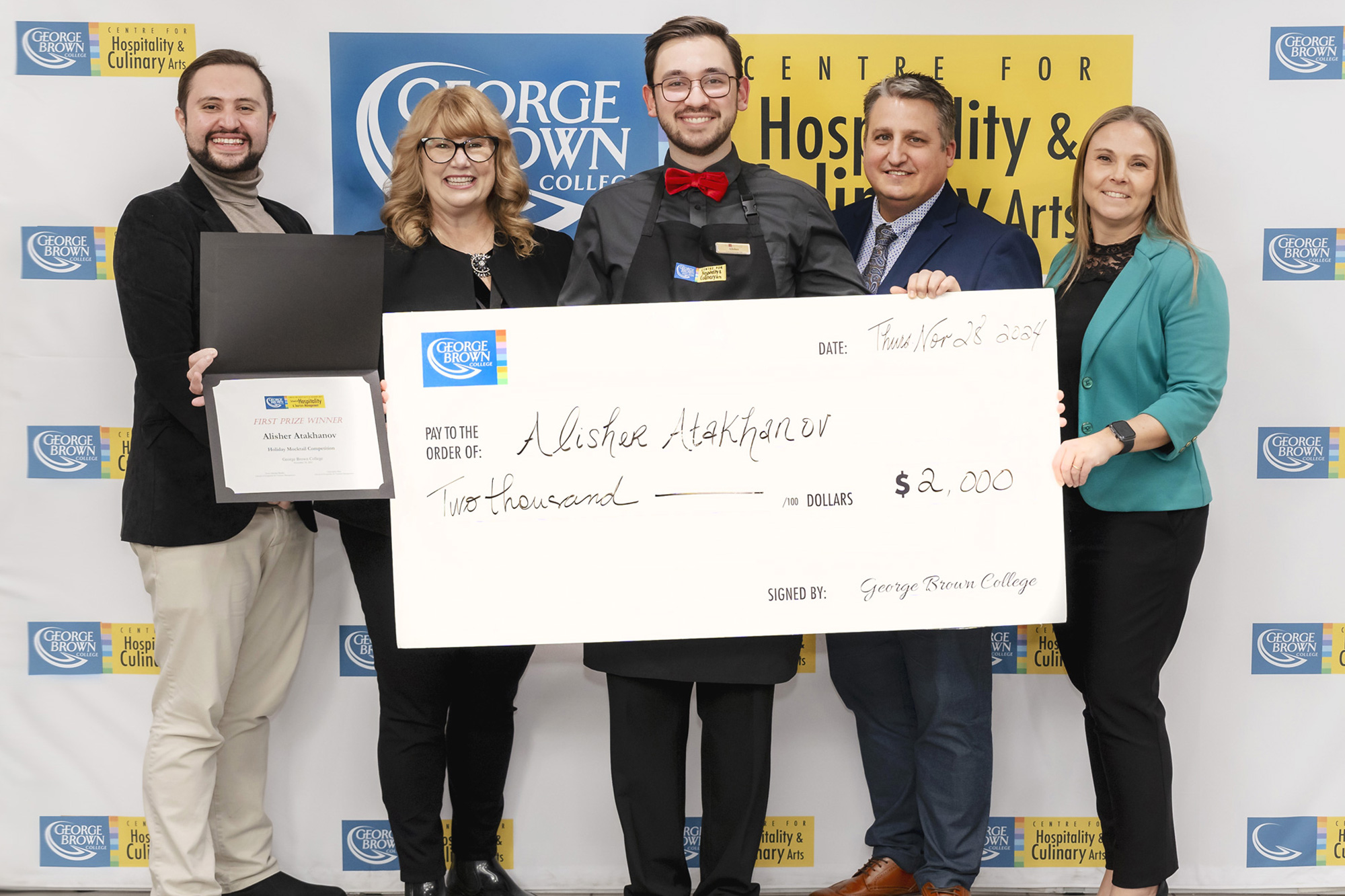 Alisher Atakhanov stands with an oversized cheque for winning the mocktail competition