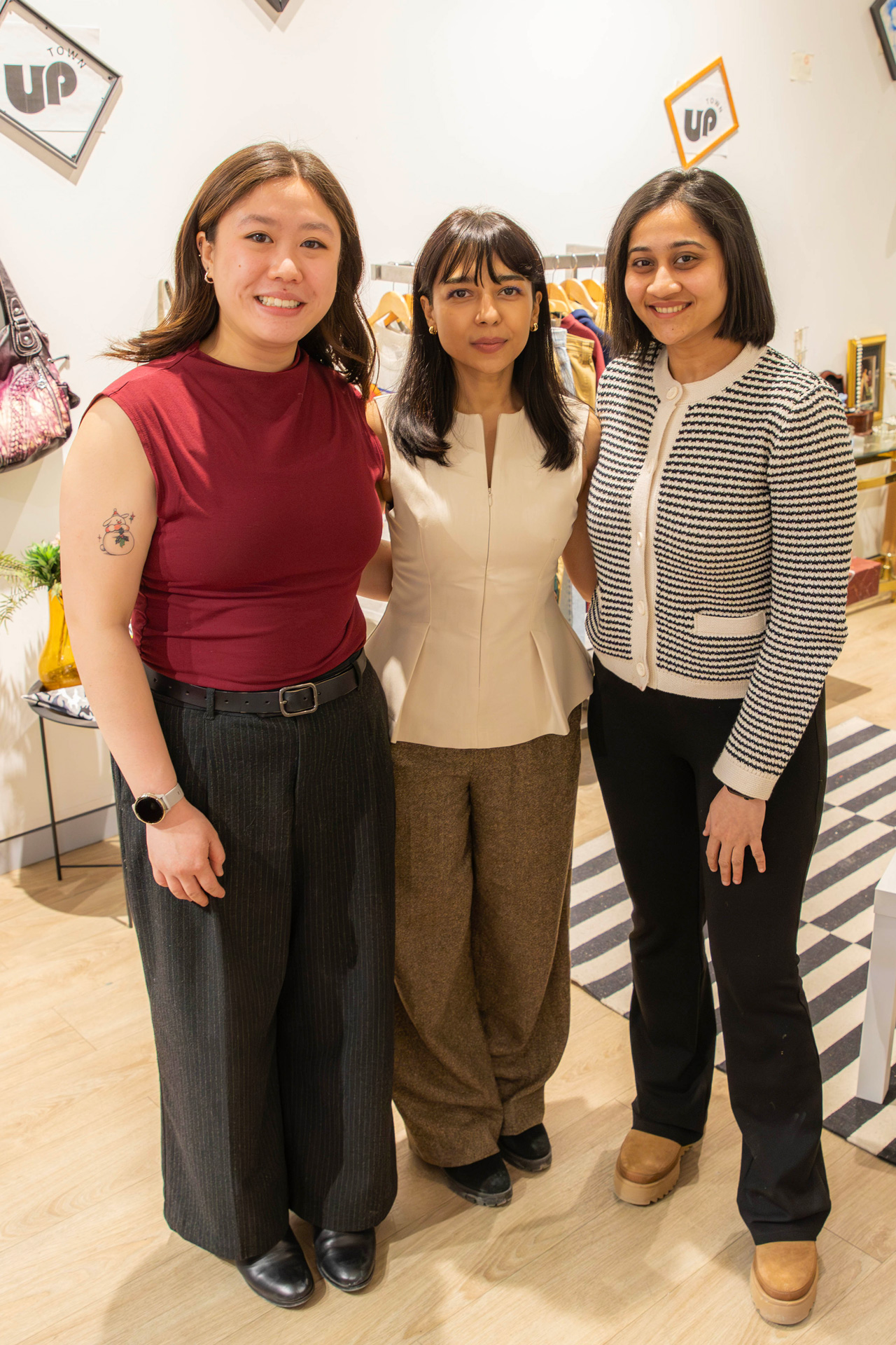 Three women stand side by side in front of the fashion store