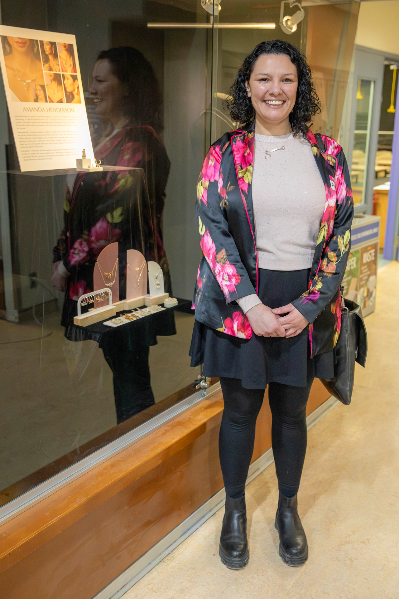 A woman stands in front of a display case, smiling.