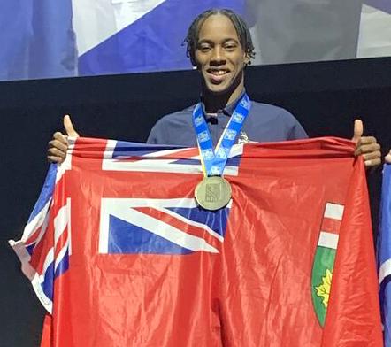 Negus King wearing Skills Canada gold medal and holding Ontario flag