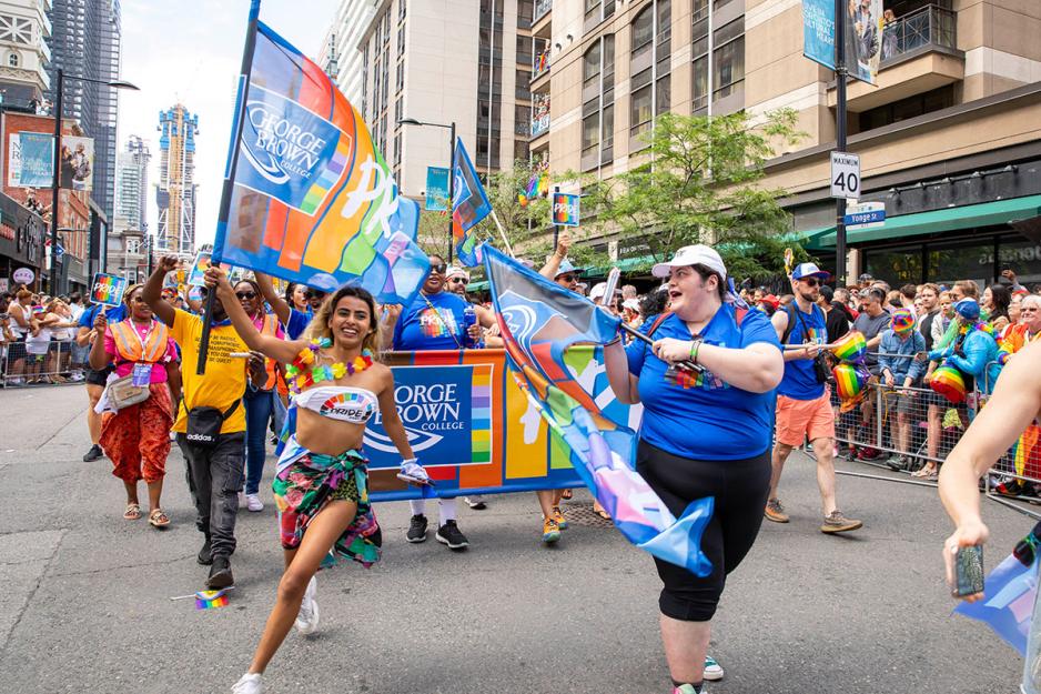 GBC marcher running with GBC Pride flag alongside other marchers, 2024
