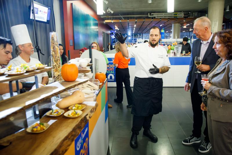 A chef speaking with guests at the Food Court Social